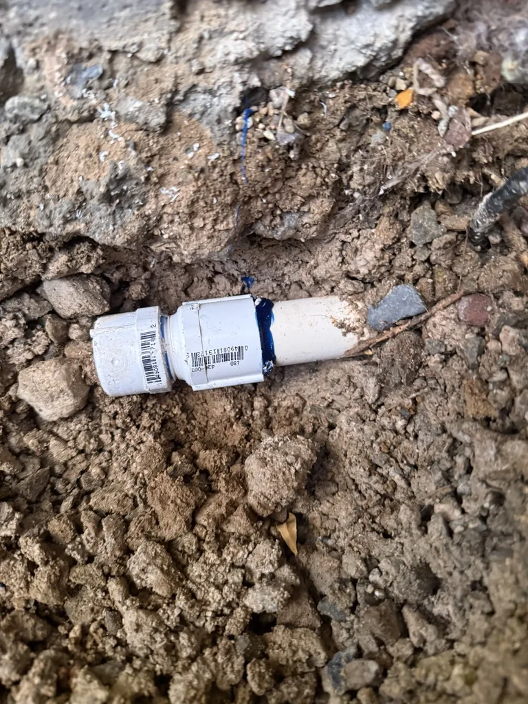 White pipe connection exposed at a Keystone backyard broken-pipe job