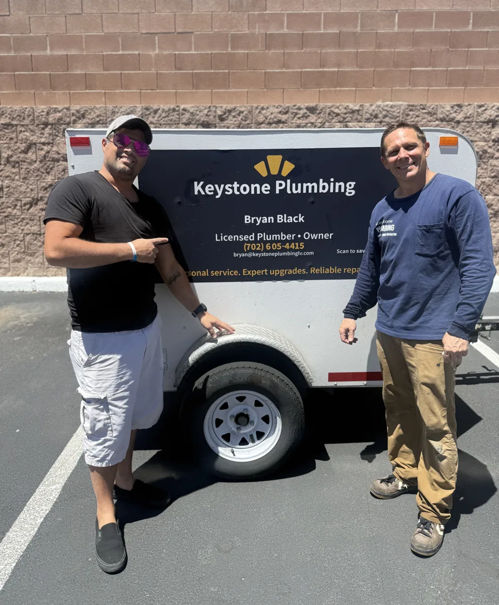 Two people standing beside the Keystone Plumbing service trailer